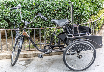 Fototapeta na wymiar Bicycle with three wheeled tied to a small metal fence
