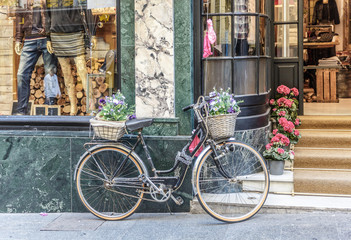 Fototapeta na wymiar Vintage bicycle with a basket in front and behind, in front of a store