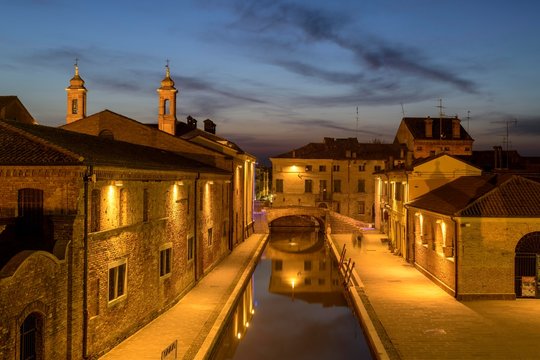 View from the Trepponti bridge on canal with village at dusk, Comacchio, Emilia-Romagna, Italy, Europe
