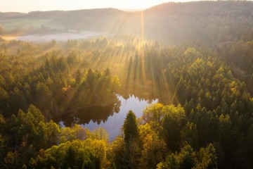 Sunrays over forest, sunrise, nature reserve Klosterfilz, Dietramszell, drone shot, Tolzer Land, Upper Bavaria, Bavaria, Germany, Europe