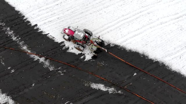 Farm tractor spreading liquid manure in snow covered field.