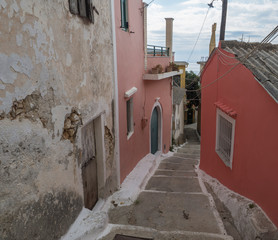 narrow street and stairs with old red houses and green door, vintage look, Corfu Greece