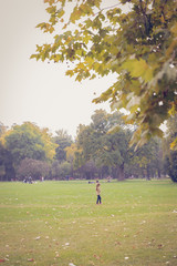 A young girl standing alone in the park. An autumn Sunday view at a public park