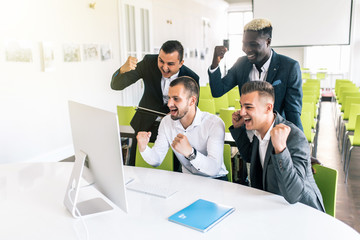 We did it. Cheerful young people looking excited while sitting at the office table at the business meeting