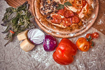 Pizza on wooden background with tomatoes, mushrooms,  basil and mozzarella cheese, close up top view