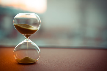 Sand running through the bulbs of an hourglass measuring the passing time in a countdown to a deadline, on a blur background with copy space