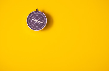 Black compass on yellow background, equipment for travel, tourism and business, top view and copy...