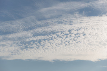 Beautiful puffy clouds on the blue sky like painted with sunset light. 