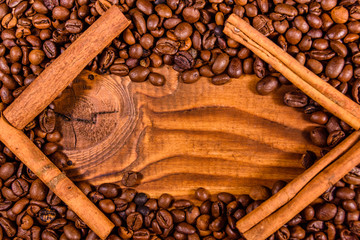 Frame of coffee beans and cinnamon sticks on wooden table