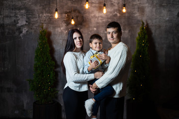 New year's portrait of a happy family near Christmas trees and walls