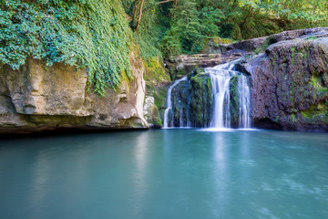 Fototapeta premium Beautiful stream waterfalls cascade over pretty green moss covered stones
