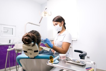 Girl dentist examines the teeth of a patient in a dental clinic