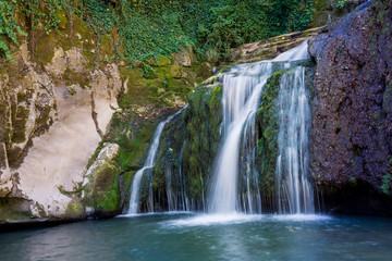 Fototapeta na wymiar Beautiful stream waterfalls cascade over pretty green moss covered stones