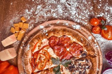 Pizza on wooden background with tomatoes, mushrooms,  basil and mozzarella cheese, close up top view