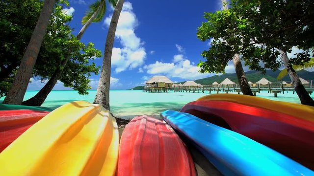 Canoe boats Palm trees Overwater Bungalows in tropical aquamarine lagoon a luxury vacation resort in Bora Bora South Pacific French Polynesia