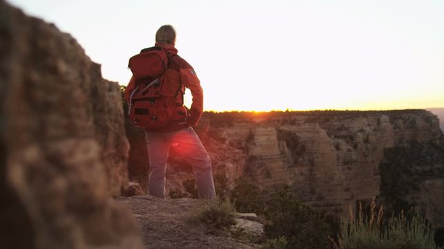 Caucasian female hiker motivated by her successful achievement viewing Grand Canyon sun flare sunset Arizona USA 