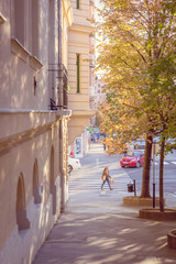View of a street in Budapest, Hungary with a soft light. A young woman crossing the street. 
