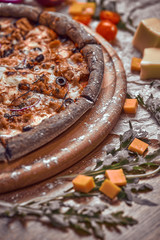 Pizza on wooden background with tomatoes, mushrooms,  basil and mozzarella cheese, close up top view