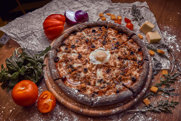 Pizza on wooden background with tomatoes, mushrooms,  basil and mozzarella cheese, close up top view