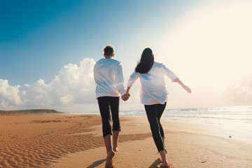 happy couple running on the beach.Young couple in love walking on the sand by the sea