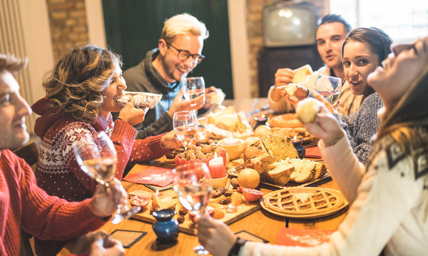 Front View Of Friends Group Tasting Christmas Sweets Food And Having Fun At Home Drinking Champagne Sparkling Wine - Winter Holidays Concept With People Enjoying Time Eating Together - Warm Filter