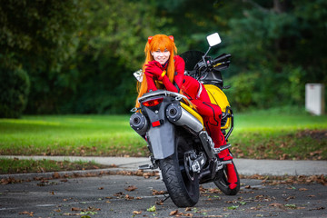 Obraz premium Young attractive girl in red posing with big motorcycle