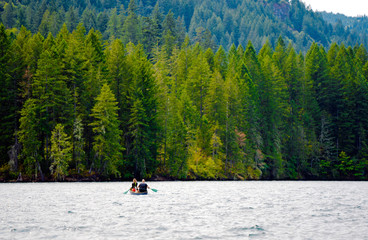 Man with girl and dog sail on boat along the picturesque mountain lake of Merwin with forest of green beaches