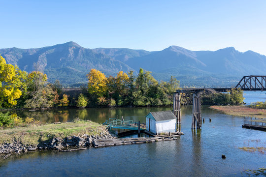 Old pier in the backwaters of the Columbia River with yellowed autumn trees
