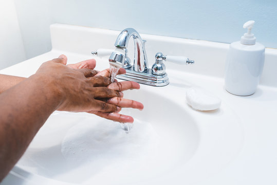 African american man washing hands in bathroom white sink and silver faucet