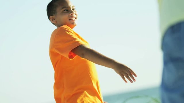 Carefree African American parent male and son throwing the frisbee on the beach RED EPIC