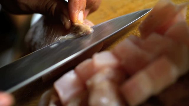 Balinese Chef cutting up uncooked local Mahi Mahi fish on wooden chopping board with knife 