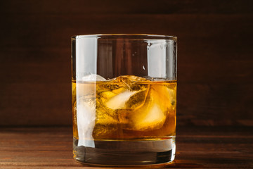 Whiskey in glass with cubes of ice on dark background close up