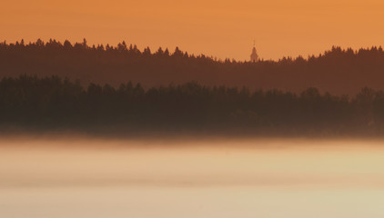 fog in the field against the forest with the Church. panoramic view