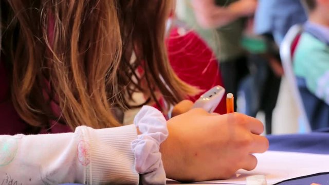 Young girl using a smartphone while drawing in school art