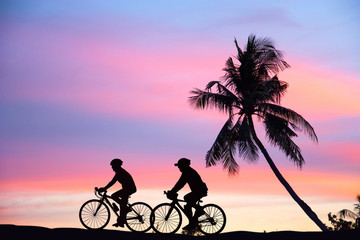 Fototapeta premium bike riding silhouette Beautiful color The sun sets Coconut tree near