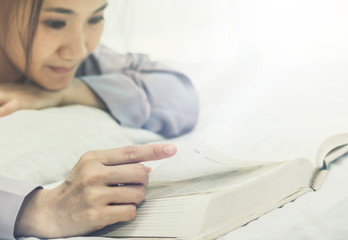 women read book to learning on bed in bed room in the morning.