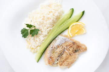 fish steak with rice, lemon and cucumber