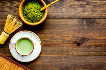 Coffee and cocktails with matcha concept. Matcha latte near bowl with matcha powder and accessories on dark wooden background top view copy space