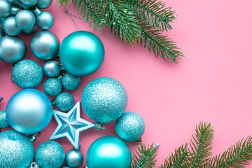 New Year and Christmas atmosphere. Decorate festive christmas tree. Christmas tree decoration. Colorful balls and stars near spruce branch, pine fir on pink background top view space for text