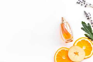 Sweet perfume with fruit fragrance. Bottle  of perfume near apple, orange, lavender on white background top view space for text border
