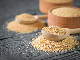 Amaranth and quinoa seeds and two wooden spoons on a table.