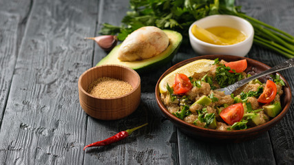 Salad of amaranth, avocado, pepper, lemon, parsley with bowl seeds on a black table.