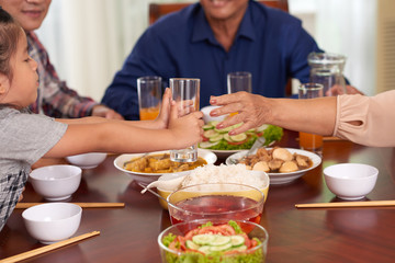 Child giving glass to his grandmother at family dinner