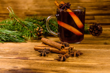 Cup of mulled wine with cinnamon and fir tree branches on wooden table
