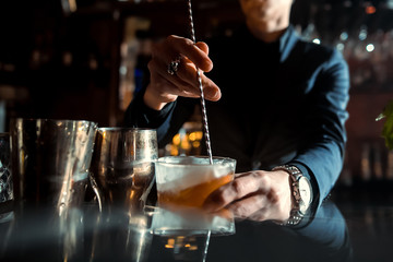 Expert Bartender is making cocktail at bar.