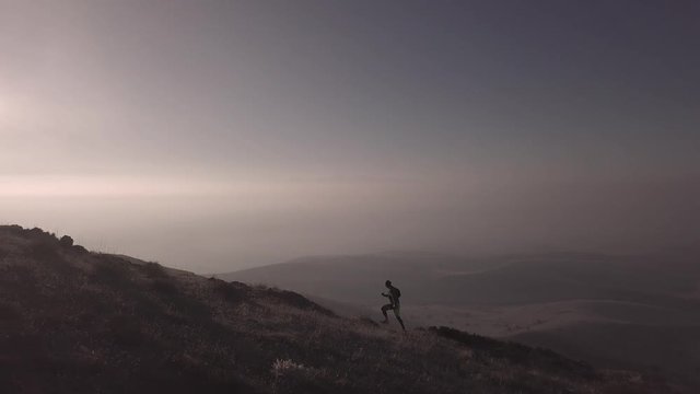 man is running in mountains in sunset