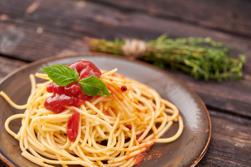 spaghetti with ketchup and Basil on dark wooden background