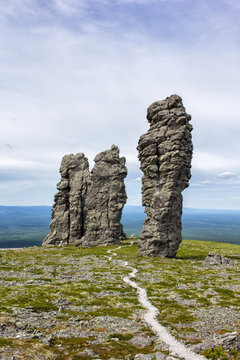 People walking along the trail on Manpupunyor, or the Exposure Poles, are a geological monument in the Northern Urals of Russia.