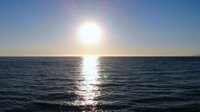 Long pullback from beautiful ocean wave sunset to empty beach with volleyball courts by aerial 4k DJI drone in Huntington Beach, Southern California.