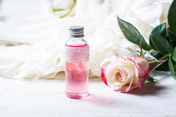 Obraz na płótnie Canvas perfumed rose water in a bottle on a wooden table